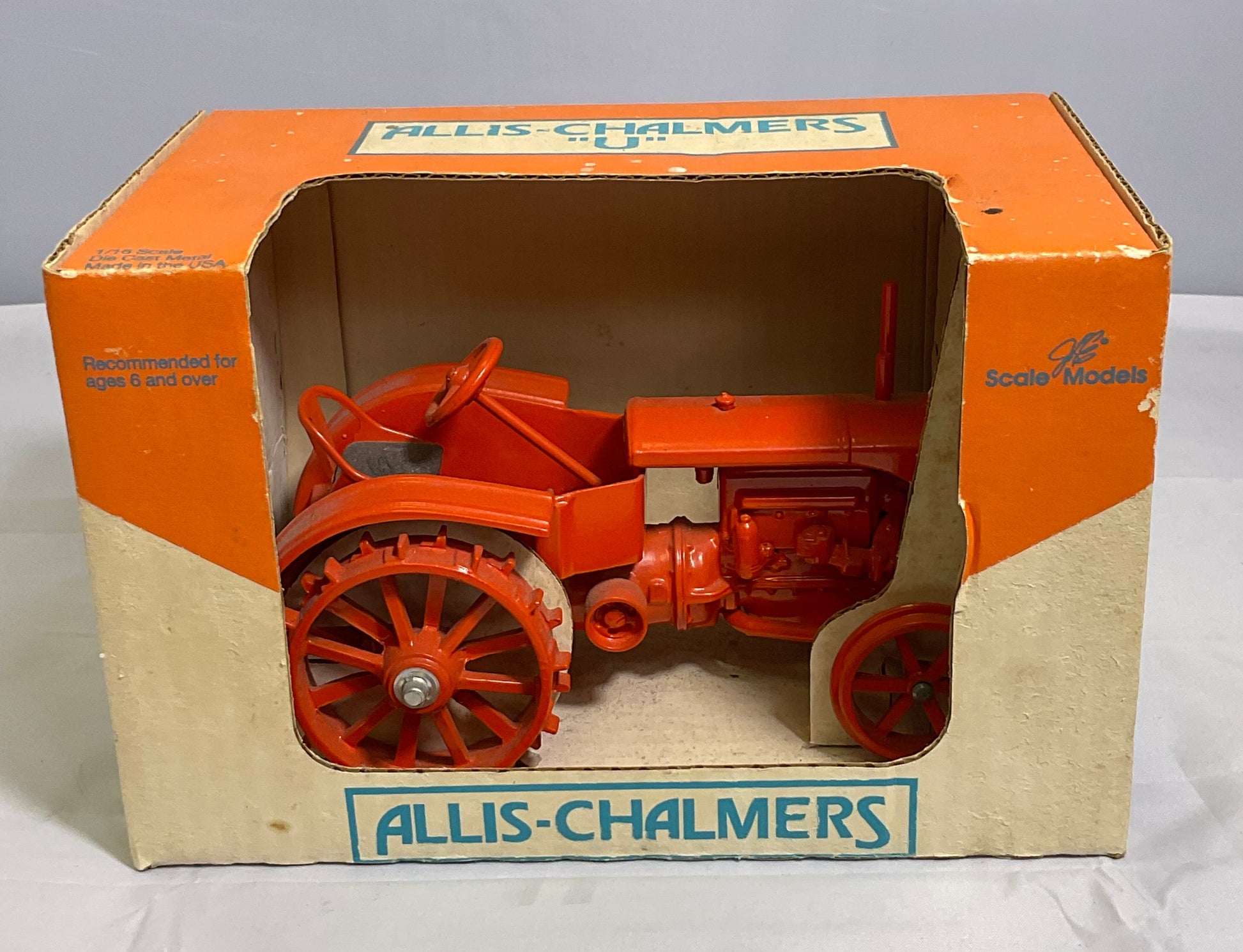 Model of a tractor in an open box with 'Allis-Chalmers' branding on a white background