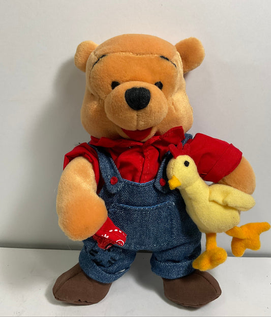 Plush toy of a bear in overalls with a duck on a white background