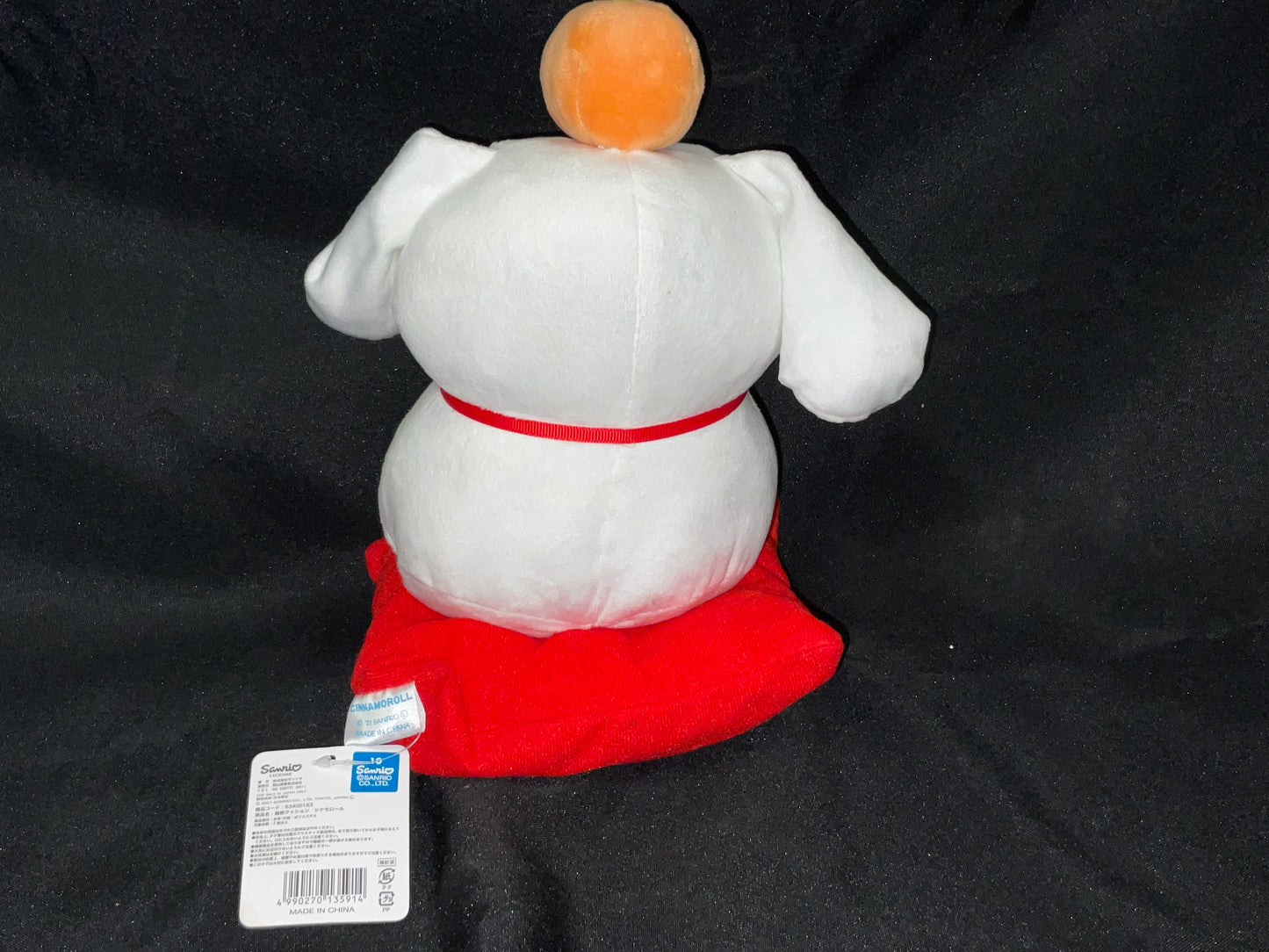 Cinnamon Roll Brand Plush Plushie Stuffie with Orange on Head Sitting on Red Pillow with Tags